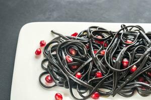 Black pasta with pomegranate seeds photo