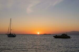 Sunset in Mykonos, Greece and yachts in the harbor photo