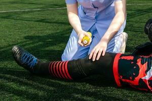 enfermero es Ayudar un fútbol americano jugador quien lesionado su pierna mientras jugando fútbol americano en el césped. foto