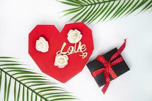 Valentine's day concept. White rose, gift box and palm leaves on white background photo