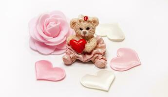 Teddy bear with red heart and pink rose on white background. photo