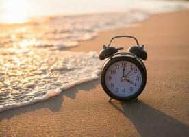 Black alarm clock on the beach in the sunset time. The concept about Time to summer, Travel, Vacation and Relaxation photo