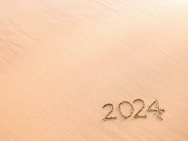 2024 año escrito en el playa en el puesta de sol tiempo. nuevo año 2024 concepto foto