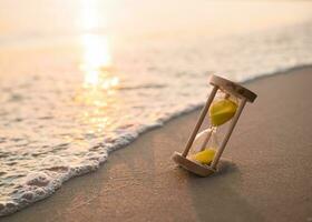 Hourglass on the beach in the sunset time. The concept about countdown to Summer, Travel, Vacation and Relaxation. photo