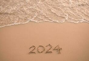 2024 año escrito en el playa en el puesta de sol tiempo. nuevo año 2024 concepto foto