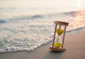 Hourglass on the beach in the sunset time. The concept about countdown to Summer, Travel, Vacation and Relaxation. photo