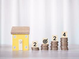 Miniature house, Wooden blocks with number 2024 on stack of coins. The concept of payment tax for house, Property investment, House mortgage, Real estate in New Year 2024. photo