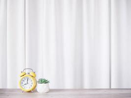 Yellow alarm clock and cactus with white curtain for background. Copy space for text, Office desk concept. photo