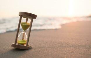 Hourglass on the beach in the sunset time. The concept about countdown to Summer, Travel, Vacation and Relaxation. photo