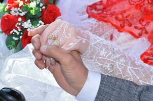 un hombre y mujer participación manos en frente de un Boda pastel foto