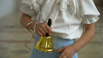 Little girl ringing a bell in the school classroom, closeup. photo