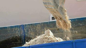 Excavator blade depositing sand in a truck. Construction video