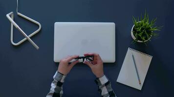 fille met sur des lunettes et départs travail à une portable tandis que séance à une table dans le après-midi. aérien tir. 4k video