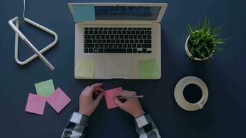 business woman comes up with business ideas and writes them down on stickers while sitting at the table. overhead shot. 4k video