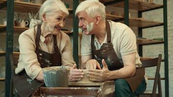 cerámica arte, mayor pareja, mutuo apoyo, mayor edad. un mayor marido ayuda un mayor mujer durante cerámica. video