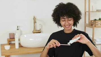Haut Pflege, Kosmetika beim heim, natürlich Creme, Spa Behandlungen, gemischt Wettrennen. schön afro amerikanisch Frau bewirbt sich Zahnpasta zu Bürste und lächelnd video
