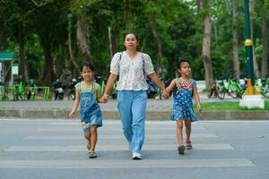 madre y niños participación manos cruzar el la carretera en el paso de peatones. la carretera tráfico la seguridad concepto. foto