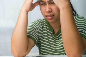 Young woman having headache against white curtain background in room. An adult woman touching head because of headache or migraine. Hands on head. photo