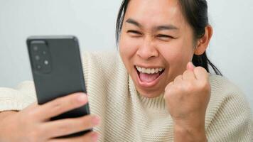 Portrait of happy woman enjoying success on mobile phone at home. Close-up of happy young woman reading good news on the phone. Surprised woman celebrating success on the phone. photo