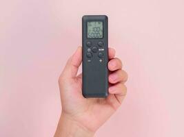 Hand holding remote control isolated on pink background. Remote control in human hand. photo