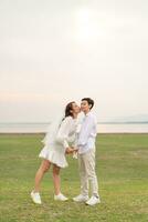 Happy young Asian couple in bride and groom clothing photo