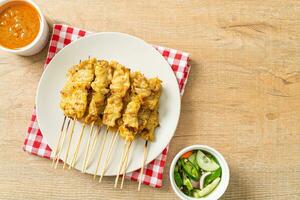 Pork satay with peanut sauce pickles which are cucumber slices and onions in vinegar photo