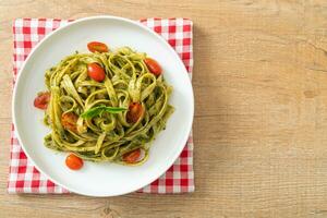 fettuccine spaghetti pasta with pesto sauce and tomatoes photo