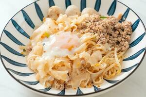 dried spicy noodles with minced pork, meatballs and egg photo