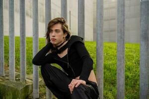 young man sitting with a lost look and dark clothing. photo