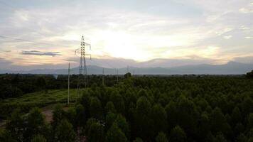 Aerial view of high voltage pylons and wires in the sky at sunset in the countryside. Drone footage of electric poles and wires at dusk. photo