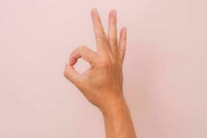 Female hand showing okay gesture isolated on pink background. photo