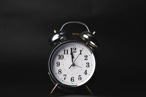 Close-up of a retro alarm clock face on a black background. Clock hands move fast, the beginning of time. photo