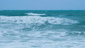 vista de las olas del mar en la playa de los mares tropicales en Tailandia. las fuertes olas del mar chocan contra la costa en la temporada de lluvias. hermosas olas del mar con espuma de color azul y turquesa. foto
