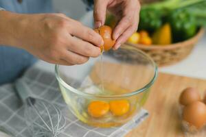 Young woman cooking in a bright kitchen, hand made cracked fresh egg yolks dripping into the bowl. Preparing ingredients for healthy cooking. Homemade food photo