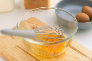 Woman beating eggs in a glass bowl. Young woman cooking in the kitchen. photo