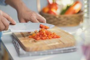 Cooking - Chef's hands are cutting tomatoes on the chopping board in the kitchen. Preparing pork stock with vegetables  in a pot. Homemade bouillon recipe. photo