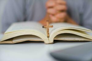 Close-up of a woman reading an open bible, praying and holding hands on her bible. Spiritual or bible study concept. photo