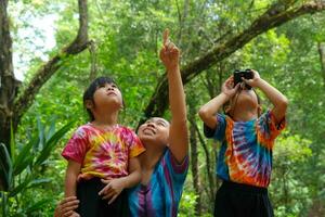 Mother and daughter doing activities while watching binoculars on vacation together. Mother and two daughters hiking using binoculars for study. Learn nature on vacation at nature trails. photo