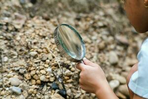 Cute little girl playing with stones and exploring with a magnifying glass. Little girl studying various natural materials. Alternative education or homeschooling. photo