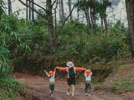 mujer joven feliz con su hija caminando juntos en un viaje de campo en las montañas. familia en una aventura de senderismo por el bosque. los padres enseñan a sus hijos sobre la naturaleza y las plantas. foto