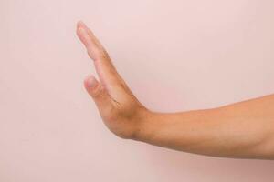 Close-up male hand with stop gesture isolated on pink background. photo