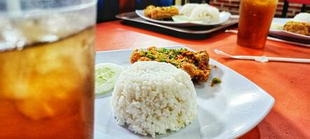 ayam geprek indonesio alimento, crujiente frito pollo con picante chile salsa y blanco arroz. selectivo atención foto