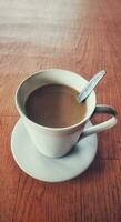 Hot coffee in a white coffee cup is placed on a wooden table in a warm and light atmosphere photo