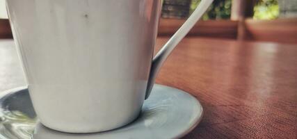 blanco café taza metido en un marrón de madera mesa foto