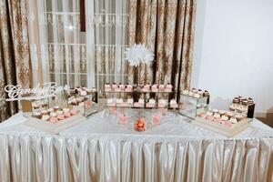 A delicious wedding. Candy bar for a banquet. Celebration concept. Fashionable desserts. Table with sweets, candies. candy bar in pink style photo