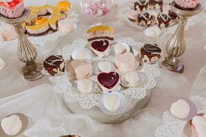 Festive dessert table with sweets. Wedding candy bar, various cakes, chocolates on stands. photo