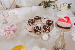 Festive dessert table with sweets. Wedding candy bar, various cakes, chocolates on stands. photo