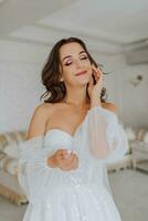 a fragile and elegant bride with long brown hair in a wedding dress poses for a photographer. A child in a hotel room. Portrait with natural light photo