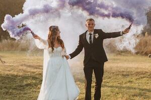 brides play with colored smoke in purple hands. Smoke bombs at a wedding. photo