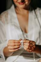 Portrait of the bride with studio light in her room. A girl in a white coat shows off her ring. Hands close up photo